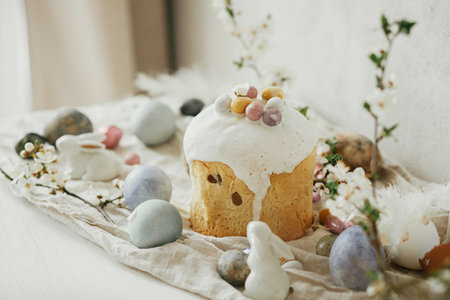 Happy Easter! Stylish easter eggs, cake, bunnies, cherry blossom on rustic table. Modern natural dyed eggs, holiday food and spring flowers. Easter countryside still lifeの写真素材