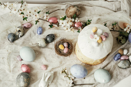 Happy Easter! Stylish easter eggs, cake, cherry blossom flat lay on rustic table. Modern natural dyed eggs, holiday food and spring flowers. Easter countryside still lifeの写真素材