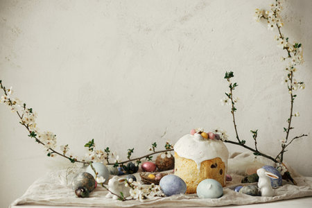 Happy Easter! Stylish easter eggs, cake, bunnies, cherry blossom on rustic table. Modern natural...