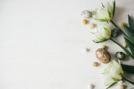 Stylish easter eggs and tulips on rustic white table. Happy Easter! Easter flat lay. Modern natural dye marble eggs and spring flowers, holiday banner. Seasons greetings, space for textの写真素材