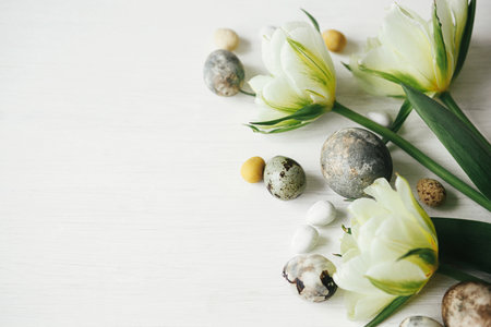 Stylish easter eggs and tulips on rustic white table. Happy Easter! Easter flat lay. Modern natural dye marble eggs and spring flowers, holiday banner. Seasons greetings, space for textの写真素材