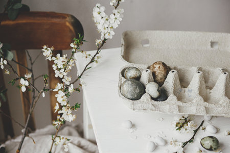 Happy Easter! Stylish easter eggs in tray and cherry blossom on rustic table. Modern natural dye marble eggs and spring flowers still life. Rural easter compositionの写真素材