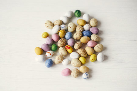 Stylish colorful easter eggs flat lay on rustic white table. Natural candy chocolate eggs. Happy...