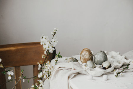 Stylish easter eggs in tray and cherry blossom on rustic white table. Happy Easter! Easter country still life. Modern natural dye marble eggs and spring flowers, holiday bannerの写真素材