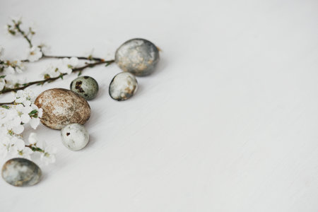 Happy Easter! Stylish easter eggs and cherry blossom on rustic white table. Modern natural dye marble eggs and spring flowers. Minimal easter border template with space for textの写真素材