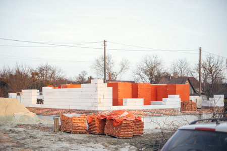 Autoclaved aerated blocks on concrete foundation and bricks, process of house building. Building materials at construction site. Stacks of white aerated blocks for laying.の写真素材