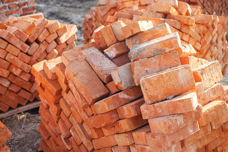 Stack of red bricks, process of house building. Bricks for laying on concrete foundation. Building materials at construction siteの写真素材