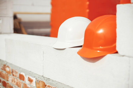 Hard hats on autoclaved aerated concrete blocks at construction site. Architecture and development. Safety helmets on white blocks. House building conceptの写真素材
