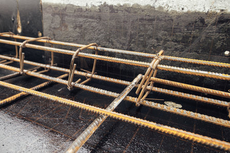 Steel rebar mesh close up. Reinforcement rods at construction site. Rusty steel reinforcement bars for concrete foundation or ceiling. Process of house buildingの写真素材