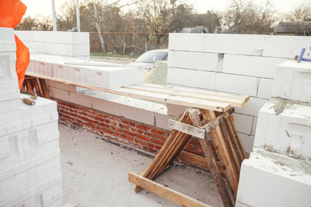 Masonry. Laying autoclaved aerated concrete blocks with reinforcement and adhesive. Installing white blocks close up.  Process of house building at construction siteの写真素材