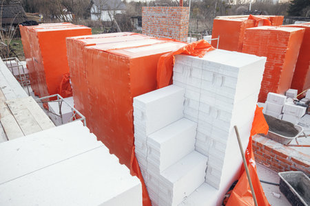 Autoclaved aerated blocks on concrete foundation, process of house building. Stacks of white aerated blocks for laying on concrete foundation. Building materials at construction siteの写真素材