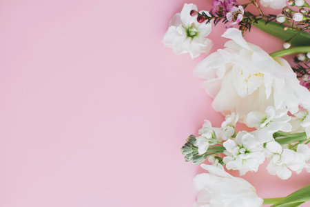 Stylish flowers flat lay on pink background with space for text. Happy womens day and Mothers day. Beautiful tulips and spring flowers border, greeting card template. Floral bannerの写真素材