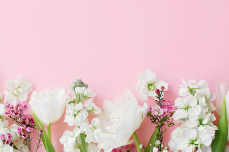 Happy Mothers day. Stylish flowers flat lay on pink background with space for text. White tender tulips and spring flowers border, greeting card template. Floral banner. Happy Womens dayの写真素材