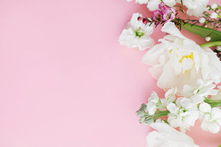 Happy Mothers day and Womens day. Stylish white flowers flat lay on pink background, space for text. Beautiful tender tulips and spring flowers border, greeting card template. Floral bannerの写真素材