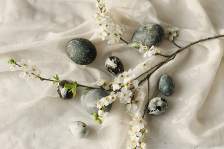 Happy Easter! Stylish easter eggs and spring flowers on linen cloth on rustic white table. Easter modern simple flat lay, space for text. Natural painted marble eggs. Seasons greetingsの写真素材