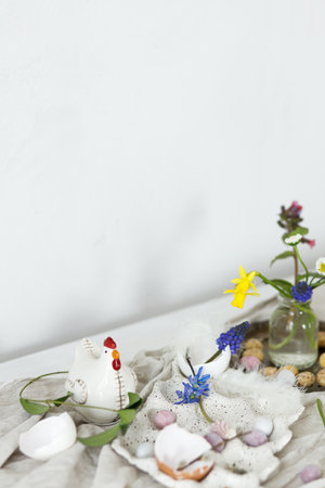 Happy Easter! Stylish easter chocolate eggs, spring flowers, chicken figurines and linen cloth on rustic wooden table. Space for text. Easter modern simple decorationの写真素材