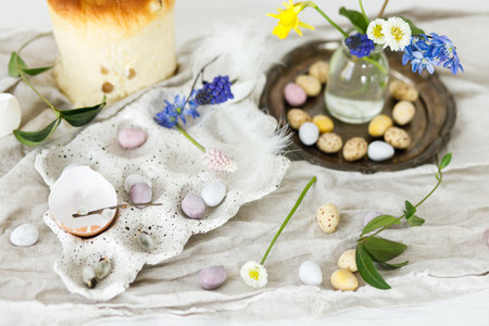 Colorful easter chocolate eggs, easter bread, spring flowers and linen cloth on rustic wooden table. Easter modern simple decoration and homemade traditional cake. Happy Easter!の写真素材