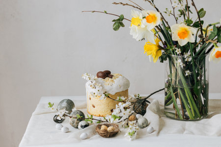 Happy Easter! Stylish easter eggs, homemade easter bread and spring flowers on linen napkin on rustic table. Natural painted marble eggs and daffodils bouquet, minimal still lifeの写真素材