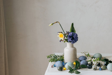 Happy Easter! Stylish easter eggs and spring flowers on linen napkin on rustic table. Natural painted marble and blue eggs, hyacinth blooms and daffodils. Modern minimal still lifeの写真素材