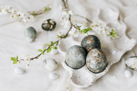 Stylish Easter eggs and spring flowers on rustic table. Happy Easter! Natural dye marble eggs in tray and cherry blossoms. Happy Easter! Holiday minimal still lifeの写真素材