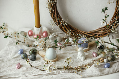 Stylish easter eggs, bunnies and cherry blossom composition on rustic table. Happy Easter! Modern...