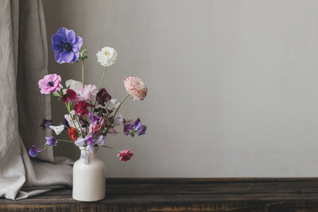 Stylish bouquet on rustic wooden bench. Beautiful colorful anemone, ranunculus, lathyrus in vase. Summer flowers, floral still life. Happy Mothers day, space for textの写真素材