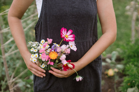 Flower farm. Beautiful flowers in rustic apron pocket close up. Woman florist gathering flowers from urban organic garden. Homestead sustainable lifestyleの写真素材