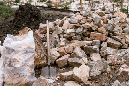 Pile of stones for pathway in cottage garden. Close up of rocks and concrete, making edge for path in modern urban gardenの写真素材