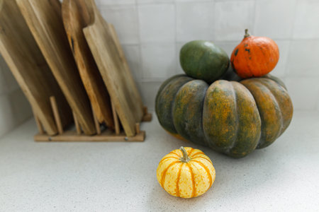Pumpkins and wooden cutting board on modern kitchen countertop. Autumn harvest and pumpkin recipes. Space for text. Thanksgiving home made foodの写真素材