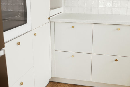 Modern kitchen interior. Stylish white kitchen cabinets with brass knobs and electric oven close up in new scandinavian house. Modern minimal kitchen designの写真素材