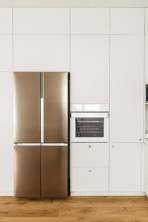 Modern minimal kitchen design. Stylish white kitchen cabinets with brass knobs, granite counter and appliances in new scandinavian house. Modern kitchen interior.の写真素材