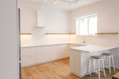 Modern minimal kitchen design. Stylish white kitchen cabinets with brass knobs, faucet, granite island and wooden shelves in new scandinavian house. Modern kitchen interior.の写真素材