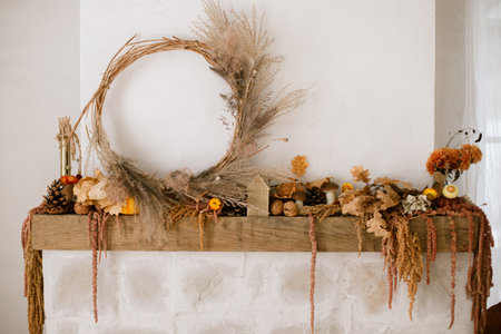 Stylish autumn decor of fireplace mantel in living room. Pumpkins, autumn leaves, wreath, pine cones, candle on rustic wood on fireplace. Fall season decoration. Thanksgiving and Halloweenの写真素材