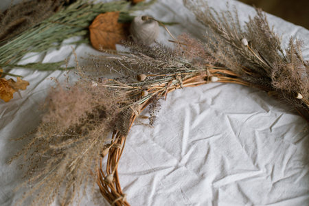 Dried grass, herbs, leaves, ribbon and scissors on rustic table. Details of making stylish autumn wreath. Fall decor and arrangement in home. Thanksgiving and Halloweenの写真素材
