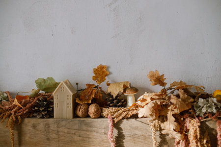 Stylish autumn decor of fireplace mantel in living room. Pumpkins, autumn leaves, nuts, candle on rustic wood on fireplace. Fall season decoration. Thanksgiving and Halloweenの写真素材