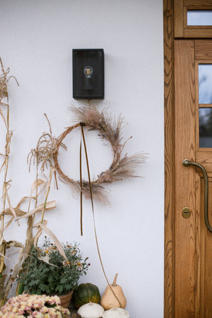 Fall decor of farm house entrance. Rustic wreath, pumpkins, moms flowers, corn at front door. Thanksgiving and Halloween. Rural autumn decorationの写真素材