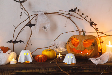 Happy Halloween! Scary pumpkin, glowing ghosts, spiders and bats on table. Halloween decor with spooky Jack o lantern and candles, space for text. Trick or treatの写真素材