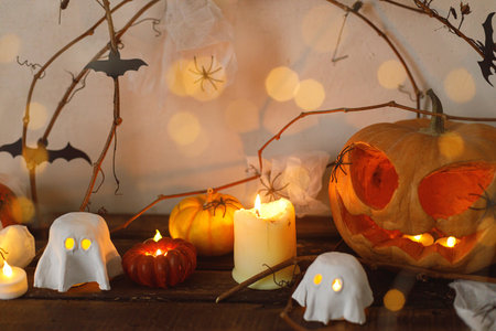 Happy Halloween! Scary pumpkin, glowing ghosts, spiders and bats on table. Halloween decor with spooky Jack o lantern and candles, space for text. Trick or treatの写真素材