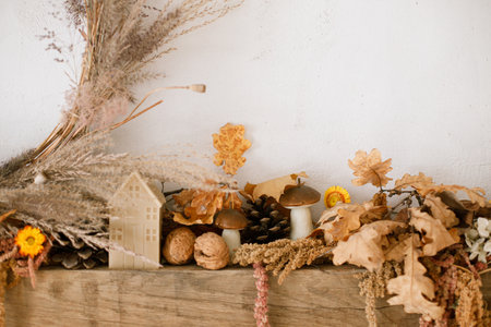 Stylish autumn decor of fireplace mantel in living room. Pumpkins, autumn leaves, nuts, candle on rustic wood on fireplace. Fall season decoration. Thanksgiving and Halloweenの写真素材