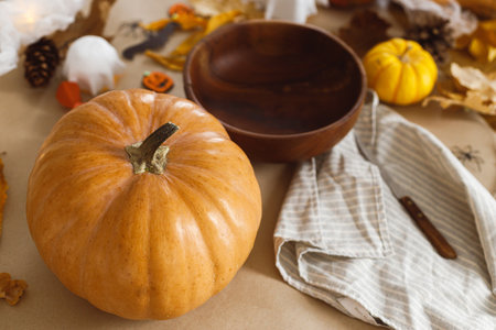 Pumpkin and knife, cobweb, ghosts and spiders on table in living room. Halloween preparation, Carve a pumpkin. Making halloween decorations, space for text.の写真素材