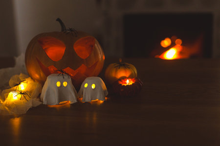 Glowing Jack o lantern and glowing ghosts with spiders in dark. Happy Halloween! Spooky atmospheric halloween decorations, space for text.の写真素材