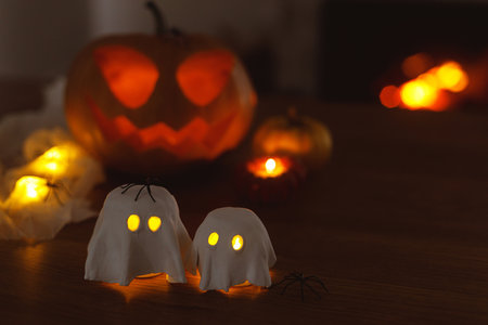 Glowing ghosts with spiders and glowing Jack o lantern in dark. Happy Halloween! Spooky atmospheric halloween decorations, space for textの写真素材