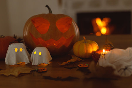 Jack o lantern carved pumpkin, glowing ghosts and spiders on table in evening. Spooky atmospheric halloween decorations, space for text. Happy Halloween!の写真素材