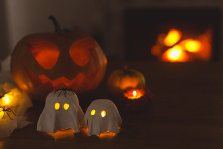 Happy Halloween! Glowing ghosts with spiders and glowing Jack o lantern in dark. Spooky atmospheric halloween decorations, space for textの写真素材