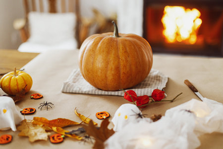 Halloween preparation. Pumpkin and knife, cobweb, ghosts and spiders on table in living room. Making halloween decorations, space for text. Carve a pumpkinの写真素材
