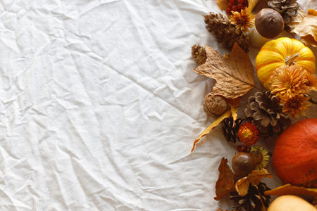 Autumn flat lay. Pumpkins, fall leaves and flowers, berries and pine cones on linen cloth on table. Fall harvest, space for text. Thanksgiving background templateの写真素材