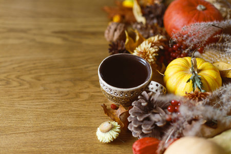 Thanksgiving background. Cup of tea, pumpkins, fall leaves and flowers, berries and pine cones on wooden background with space for text. Autumn banner. Fall harvestの写真素材