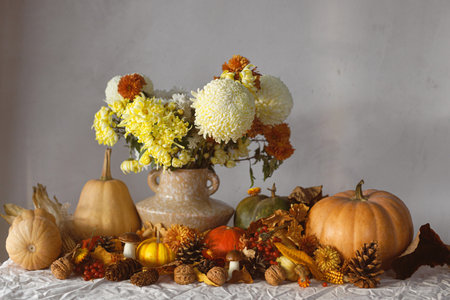 Happy Thanksgiving. Autumn still life. Pumpkins and chrysanthemum in vase, fall leaves, berries and pine cones on table. Fall harvest background, space for text.の写真素材