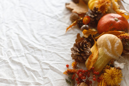 Autumn flat lay. Pumpkins, fall leaves and flowers, berries and pine cones on linen cloth on table. Fall harvest, space for text. Thanksgiving background templateの写真素材