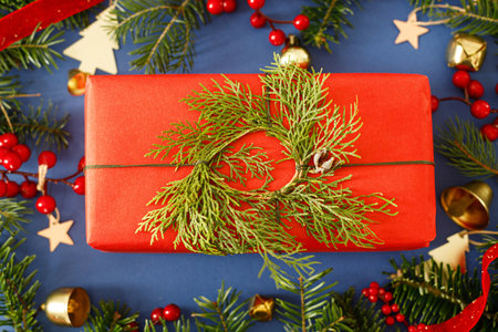 Merry Christmas! Stylish Christmas gift flat lay with cedar wreath and green fir branches, red berries and gold ornaments on blue background. Xmas background. Season's greetingsの写真素材